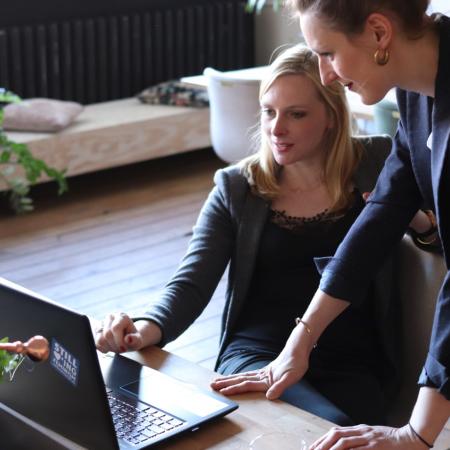 Two women looking at a black laptop